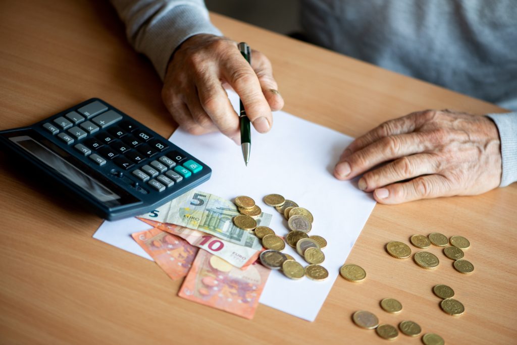 Hands Of Old Senior Man With Calculator And Bills Counting Euro Money At Home. - Advocacia em Chácara Santo Antônio - SP | Glória Rabelo